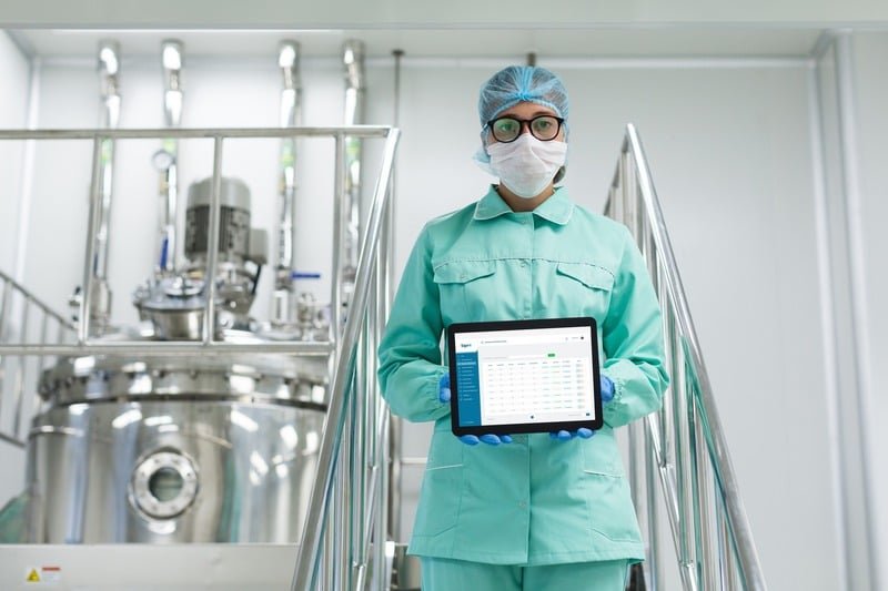 Supervisora de planta con uniforme verde revisando información en una tablet